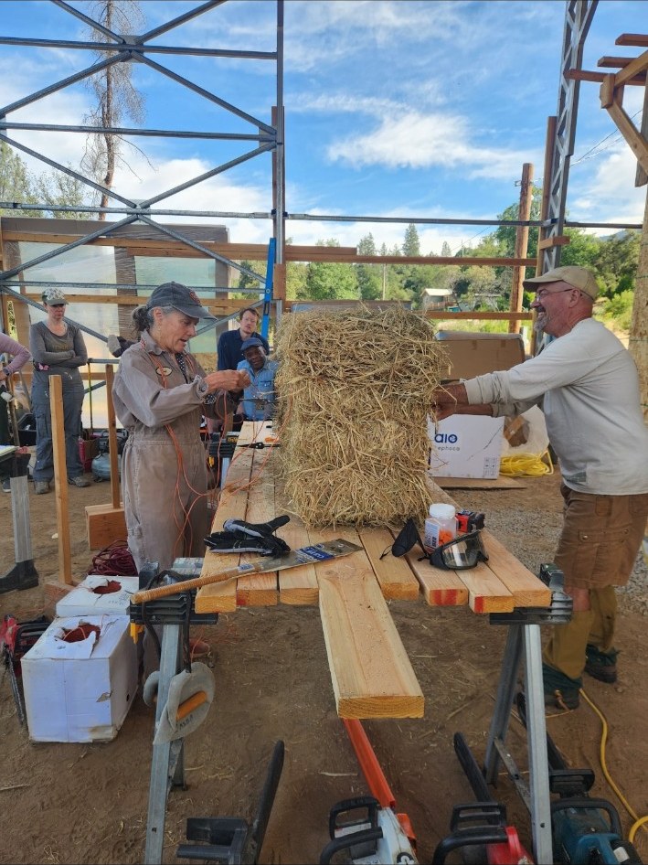 Participants working with straw bale and wood framing at a natural building workshop